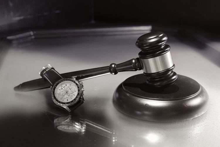 Wooden gavel and stopper beside wristwatch on wooden courtroom desk