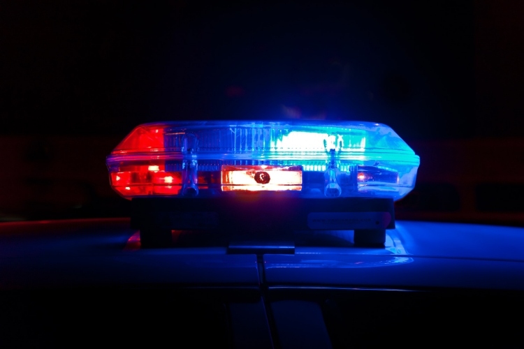 Red and blue siren on police car viewed close-up against night sky background