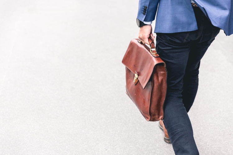 Professionally-dressed men walking on sidewalk with brown leather briefcase in hand